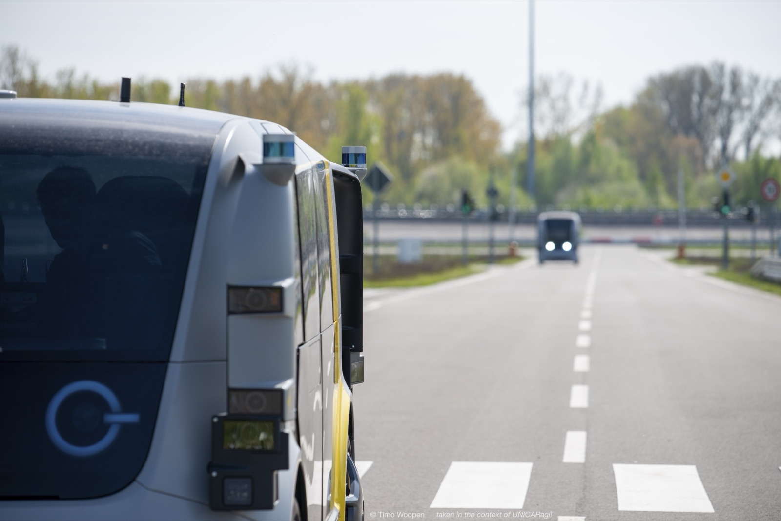 An autonomous vehicle operating on a roadway with another vehicle in the distance.